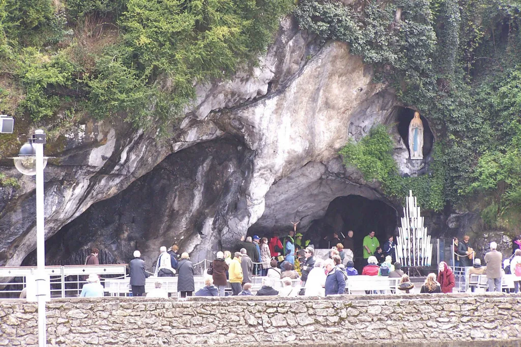 La grotte de Massabielle à Lourdes, avec la statue de la Vierge et des pèlerins en prière