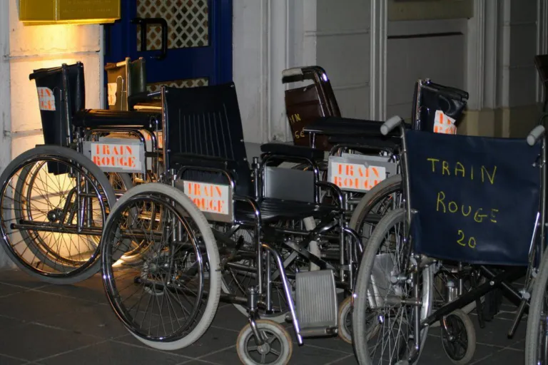 Fauteuils roulants marqués « Train Rouge » alignés, prêts pour le voyage
