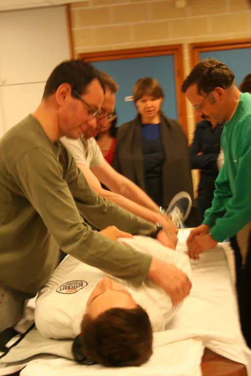 Formation au brancardage : un bénévole s'exerce auprès d'une personne allongée