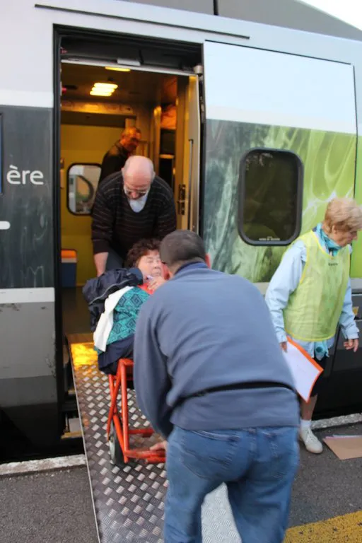 Des hospitaliers aident un pèlerin à monter dans le train