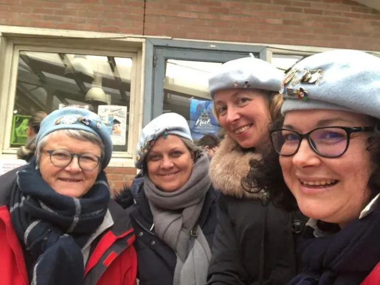 Quatre hospitalières en béret, souriantes, prennent une photo ensemble